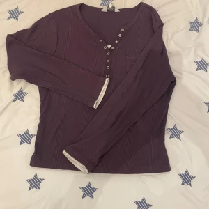 Lila ribbad tröja från Paramour Collection - Säljer en snygg lila ribbad tröja från Paramour Collection. Tröjan har långa ärmar och knappar framtill samt en liten bröstficka. Perfekt nu till våren och sjukt gullig.