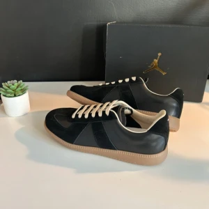Svarta sneakers med beige sula - Snygga svarta sneakers med beige sula och vita snören. Perfekta för en stilren look. Skorna har en klassisk design med en låg profil och är bekväma för vardagsbruk.