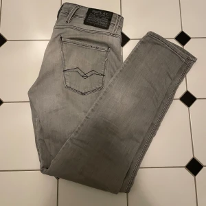 Grå jeans från Replay - Snygga grå jeans från Replay i modellen Anbass. De har en slim fit passform och är tillverkade i ett bekvämt jeansmaterial. Perfekta för en stilren look med en diskret logga på baksidan. W30 L32. Det är bara och skriv in vid funderingar!💯