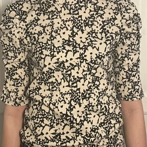 Söt Blommig topp med trekvartsärm - Säljer en stilren topp med svartvitt blommönster. Toppen har trekvartsärmar och en åtsittande passform. Hör av dig vid intresse💓