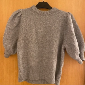 Grå stickad tröja - Mysig grå stickad tröja med puffiga trekvartsärmar och ribbade detaljer vid ärmslut och nederkant. Lite nopprig men annars fint skick, Storlek 175 men skulle säga att det är en xs, vid frågor kom privat❤️