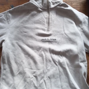 Vit tröja från Jack & Jones - Säljer en vit tröja från Jack & Jones med halv dragkedja och hög krage. Perfekt för en avslappnad stil. Tröjan har långa ärmar och är gjord i ett mjukt material.