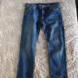 Blå jeans från Gant - Snygga blå jeans från Gant med klassisk femficksdesign och en bekväm passform. De har en dragkedja och knapp framtill samt en läderpatch med Gant-logga på baksidan. Perfekta för en stilren look.