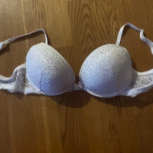 Vit spets-bh med strassdetaljer - Elegant vit bh med spets och glittrande strassdetaljer. Perfekt för att känna sig extra fin. Justerbara axelband för bästa passform.