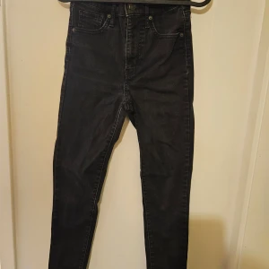 Svarta Mile High Super Skinny jeans från Levi's - Säljer ett par svarta Mile High Super Skinny jeans från Levi's. De är högmidjade och har en tight passform som framhäver benen. Perfekta för en stilren look. Klassisk femficksdesign med knapp och dragkedja framtill.