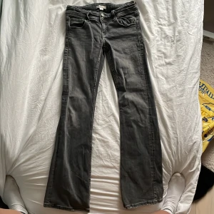 Svarta bootcut jeans - Snygga svarta bootcut jeans med klassisk femficksdesign och knappar. Perfekta för en stilren look. De har en bekväm passform och är tillverkade i ett slitstarkt material.