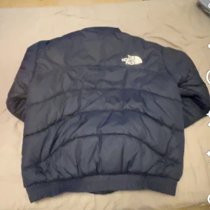 Blå dunjacka från The North Face - Säljer en blå dunjacka från The North Face. Jackan har en dragkedja framtill och är långärmad. Perfekt för kyligare väder med sin pufferdesign.