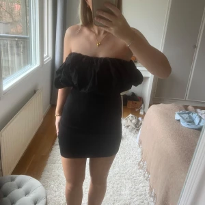 Svart offshoulder klänning från Zara - Säljer en elegant svart offshoulder klänning från Zara. Klänningen har en tight passform och volangdetaljer vid axlarna. Perfekt för en kväll ute eller en speciell tillställning. 🖤 Storlek M