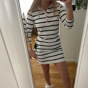 Randig skjortklänning från Gant - Säljer en snygg vit och marinblå randig klänning från Gant. Klänningen har trekvartsärmar och en stjärndetalj på fickan. Den har en krage med knappar och röda detaljer. Mycket gott skick🙌🏼