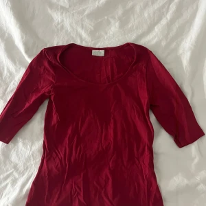 Röd topp från h&m - Säljer en snygg röd topp från h&m med trekvartsärm och rund halsringning. Perfekt för att lägga till en färgklick i garderoben. Passar bra till både jeans och kjol.