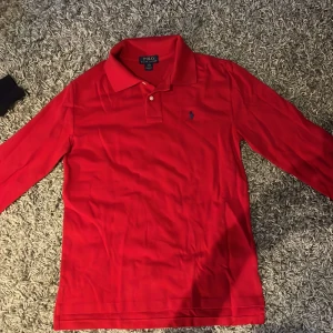 Röd pikétröja från Ralph Lauren - Säljer en klassisk röd pikétröja från Ralph Lauren med lång ärm och den ikoniska broderade loggan på bröstet. Perfekt för en stilren look. Nypris 2000
