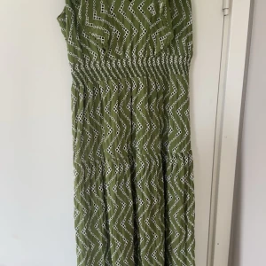 Grön mönstrad klänning från Zara - Snygg grön klänning från Zara med vitt mönster. Klänningen har korta ärmar och en smockdetalj i midjan för en bekväm passform. Perfekt för en somrig look!