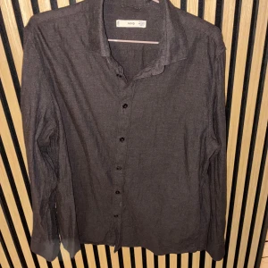 Grå skjorta från MNG - Säljer en stilren grå skjorta från MNG i storlek M. Skjortan har långa ärmar och knappar framtill. Perfekt för en klassisk look.