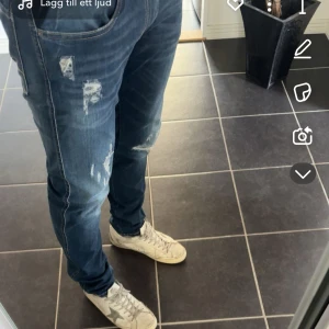 Blå jeans från Replay - Snygga blå jeans från Replay med slitna detaljer och en klassisk femficksdesign. De har en dragkedja och knapp framtill. Perfekta för en avslappnad stil. Byxorna är endast använda en till två gånger, köpta för 1600kr på jeans bolaget  säljer dom för 700kr.
