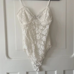 Vit spetsbody - Säljer en elegant vit spetsbody med smala axelband och vacker spetsdesign. Perfekt för att lägga till en romantisk touch till din outfit. 💕storlek M men passar mer som S