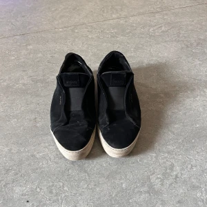 Svarta sneakers från Axel Arigato - Snygga svarta sneakers från Axel Arigato med en stilren design. Skorna har en vit sula och är tillverkade i mocka. Perfekta för en avslappnad stil.