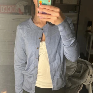 Blå kofta från Holly & Whyte - Säljer en stilren blå kofta från Holly & Whyte by Lindex. Koftan har långa ärmar och knappar framtill. Perfekt för lager-på-lager och passar till många olika outfits. 💙