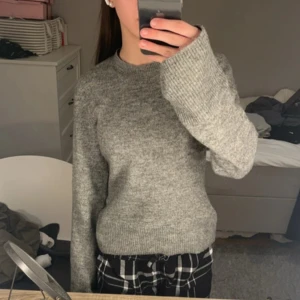 Grå stickad tröja från H&M - Säljer en mysig grå stickad tröja från H&M. Tröjan har långa ärmar och en klassisk rund halsringning. Perfekt för kyligare dagar och enkel att matcha med olika outfits. Hör av dig vid intresse! 😊