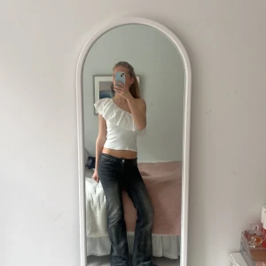 Vit offshoulder topp med volang - Säljer en söt vit offshoulder topp med en stor volangdetalj. Toppen är ribbad och har ett vackert broderat mönster på volangen. Perfekt för sommarens alla tillfällen! 💫