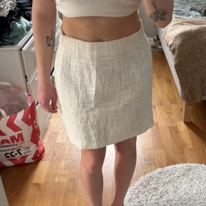 Vit kjol i linne - Snygg vit kjol i linne med en klassisk och stilren design. Kjolen har en normal passform och är perfekt för varmare dagar. Den är knälång och passar bra till både vardag och festligare tillfällen.