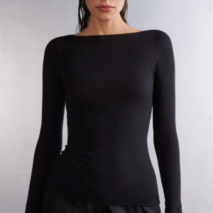 Svart intimissimi tröja - Snygg och stilren svart intimissimi med en tight passform. Perfekt för en minimalistisk look och kan enkelt matchas med olika outfits. Superfint skick lite små slitningar vid handlederna men annars inget!