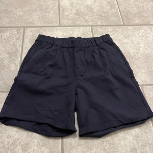 Mörkblå shorts - Säljer ett par mörkblå shorts med elastisk midja. Perfekta för en avslappnad stil. 