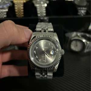 Silverfärgad klocka från Seiko - Snygg silverfärgad klocka från Seiko med automatisk urverk. Den har en klassisk design med en räfflad bezel och ett armband i rostfritt stål. Perfekt för den som gillar stilrena accessoarer.