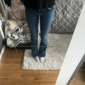 Blå bootcut jeans - Säljer ett par klassiska blå bootcut jeans med normal passform. Jeansen har en snygg och tidlös design med fem fickor och knappgylf. Perfekta för en avslappnad stil.