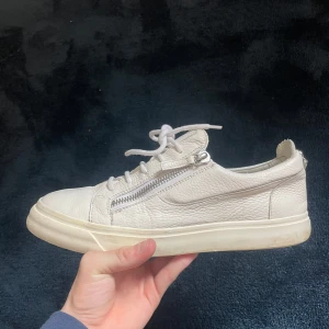 Giuseppe Zanotti sneakers - Snygga vita sneakers med snörning och dragkedja på sidan.   Storlek 43 men passar som 43,5. Skick 7/10 med tanke på creasing på toeboxen, utöver det så är dem i bra skick och är rena. Kontakta mig vid minsta fundering! Sjölvklart 100% äkta.