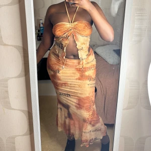 Orange tvådelad klänning - Trendig tvådelad klänning i orange med ett unikt mönster. Toppen har en knytning fram och är axelbandslös (Strl S), medan kjolen är lång (Strl M) och figurnära 🧡💛