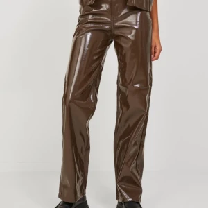 Bruna glansiga byxor - Snygga bruna byxor i glansigt material från NA-KD. De har en rak passform och hög midja, vilket ger en modern look. Perfekta för att sticka ut med sin unika stil.