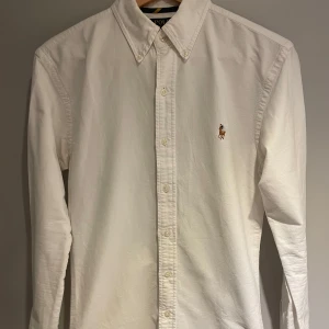 Vit skjorta från Polo Ralph Lauren - Säljer en klassisk vit skjorta från Polo Ralph Lauren med broderad logotyp på bröstet. Skjortan har inga defekter! . Perfekt för sommaren! pris går självklart att diskuteras.