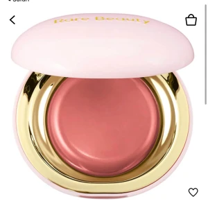 Krämrouge från Rare Beauty - Krämrouge i en elegant rund förpackning med guldiga detaljer och ett mjukt rosa lock. Perfekt för att ge kinderna en naturlig och fräsch färg. Den är i färgen Nearly Neutral. Endast testad på handen säljer den då den ej kommer till användning. Nytt pris ca 400 mitt 300