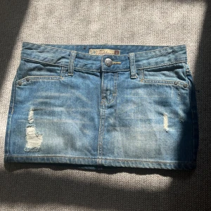 Blå mini jeanskjol från Fishbone - Snygg blå jeanskjol från Fishbone i storlek S. Kjolen har en klassisk femficksdesign med slitna detaljer framtill för en trendig look. Perfekt för en avslappnad stil. 🦋