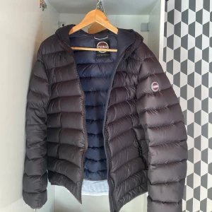 Svart dunjacka från Colmar - Snygg svart dunjacka från Colmar med huva och dragkedja. Jackan har en quiltad design och är perfekt för vårens o höstens väder. Den har långa ärmar och en stilren look, Ny pris 3000kr. ( OBS! pris är inte hugget i sten)