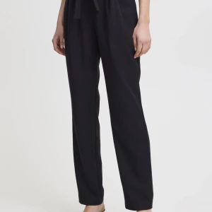 Svarta byxor med knytband - Snygga svarta byxor med knytband i midjan. Byxorna har en loose passform och är perfekta för en stilren look. Tillverkade i ett mjukt material som ger en bekväm känsla hela dagen.