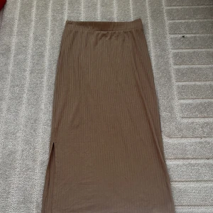 Beige ribbad kjol från Pieces - Snygg beige ribbad kjol från Pieces med en stilren slits på sidan. Säljer för att den inte kommer till användning längre. Och vill bara påpeka att den har en liten liten fläck på sig som visas på en av bilderna.