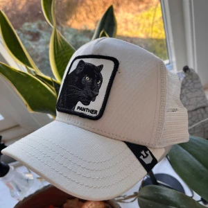 Vit keps med pantermotiv från The Farm - Snygg vit keps från The Farm med ett coolt broderat pantermotiv på framsidan. Kepsen har en klassisk design med justerbar passform och meshdetaljer för extra ventilation. Perfekt för en avslappnad stil.