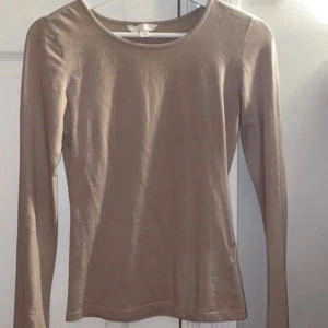 Beige långärmad topp - Säljer en stilren beige långärmad topp i mjukt material. Perfekt för lager-på-lager eller som den är. Enkel och mångsidig design som passar till det mesta. Hör av dig vid intresse!