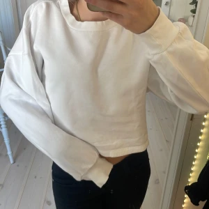 Vit croppad tröja från Gina Tricot - Säljer en vit croppad tröja från Gina Tricot. Det är en liten fläck på vänster arm men inget som syns när man har på sig den💓