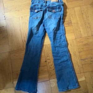 Blå bootcut jeans, storlek 140 - Snygga blå bootcut jeans med klassisk femficksdesign och dragkedja. Perfekta för en avslappnad stil med en touch av 90-tal. Passar bra med sneakers eller boots. Från lager 157, storlek 140. Använt några gånger