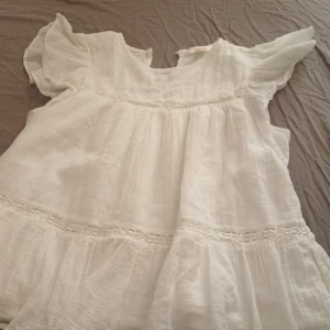 Vit blus från Gina Tricot - Säljer en söt vit blus från Gina Tricot med korta ärmar och volangdetaljer. Perfekt för en somrig look. Blusen har en luftig passform och är tillverkad i ett lätt material.