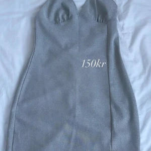 Glittrig silver klänning - Snygg glittrig klänning i silver med en tight passform. Perfekt för en kväll ute eller en fest. Klänningen har en elegant design med en smickrande siluett.