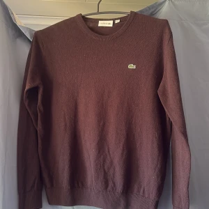 Brun tröja från Lacoste - Säljer en stilren brun tröja från Lacoste med det klassiska krokodilmärket på bröstet. Tröjan har långa ärmar och ribbade muddar vid ärmslut och nederkant. Perfekt för en avslappnad och snygg look. Priset kan diskuteras 