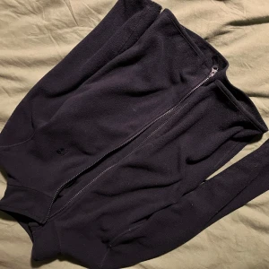 Mörkblå fleecejacka från FIX - Mörkblå fleecejacka från FIX med dragkedja framtill. Jackan har långa ärmar och är perfekt för kyligare dagar. Den är mjuk och bekväm, idealisk för både vardag och utomhusaktiviteter. Hund och katt finns i hemmet