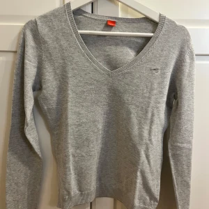 Grå v-ringad tröja från Esprit - Säljer en stilren grå v-ringad tröja från Esprit. Tröjan har långa ärmar och ribbade kanter vid hals, ärmslut och nederkant. Perfekt för en avslappnad och snygg look.