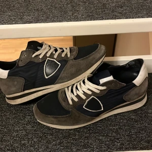 Grå och blå sneakers med mockadetaljer  - Snygga sneakers i grått och blått med mockadetaljer och vita snören. Perfekta för en avslappnad stil. Skorna har en klassisk design med en bekväm passform. Skick 6/10 