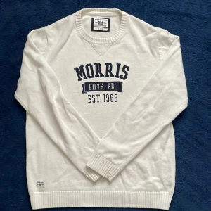 Vit tröja från Morris  - Säljer en stilren vit tröja från Morris Gents med texten 'Morris Phys. Ed. Est. 1968' tryckt på framsidan. Tröjan har långa ärmar och en ribbad krage. Perfekt för en avslappnad och sportig look. Den är storlek XL, men känns mer som L.