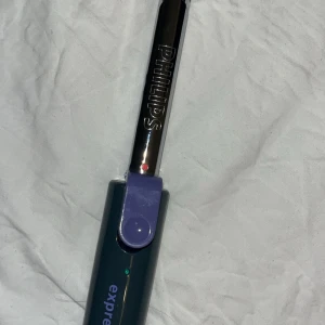 Elektrisk tändare från Philips - Snygg och praktisk elektrisk tändare från Philips i en stilren design. Den har en metallisk finish med en lila knapp för enkel användning. Perfekt för att tända ljus eller grillen utan krångel.