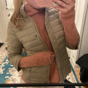 Trekvartsärmad jacka  - Säljer en snygg beige pufferjacka med dragkedja. Jackan har en normal passform och är perfekt för kyligare dagar. Den är stilren och lätt att matcha med olika outfits.
